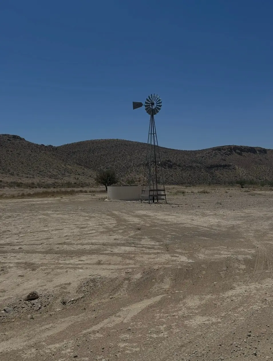 Un mulino a vento in mezzo al deserto, con le montagne dietro